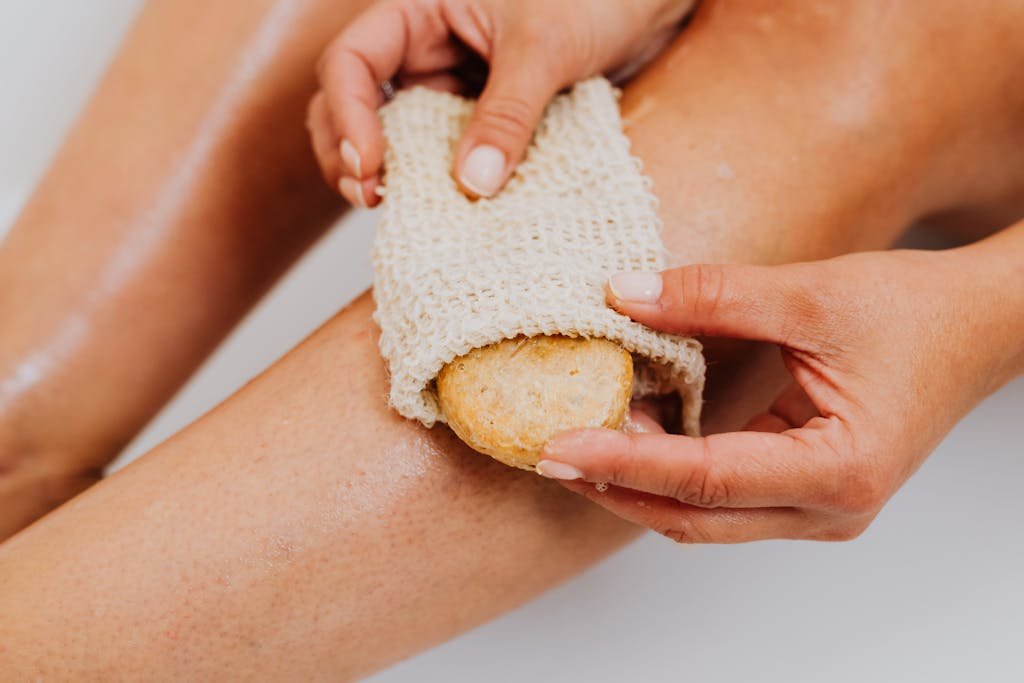 Person Using a loofah Body Scrub Sponge on Legs