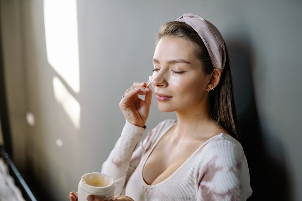 Photo of a Woman Applying Cream on Her Face