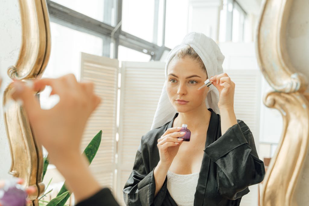 Woman in Black Robe Holding a Dropper and a Bottle